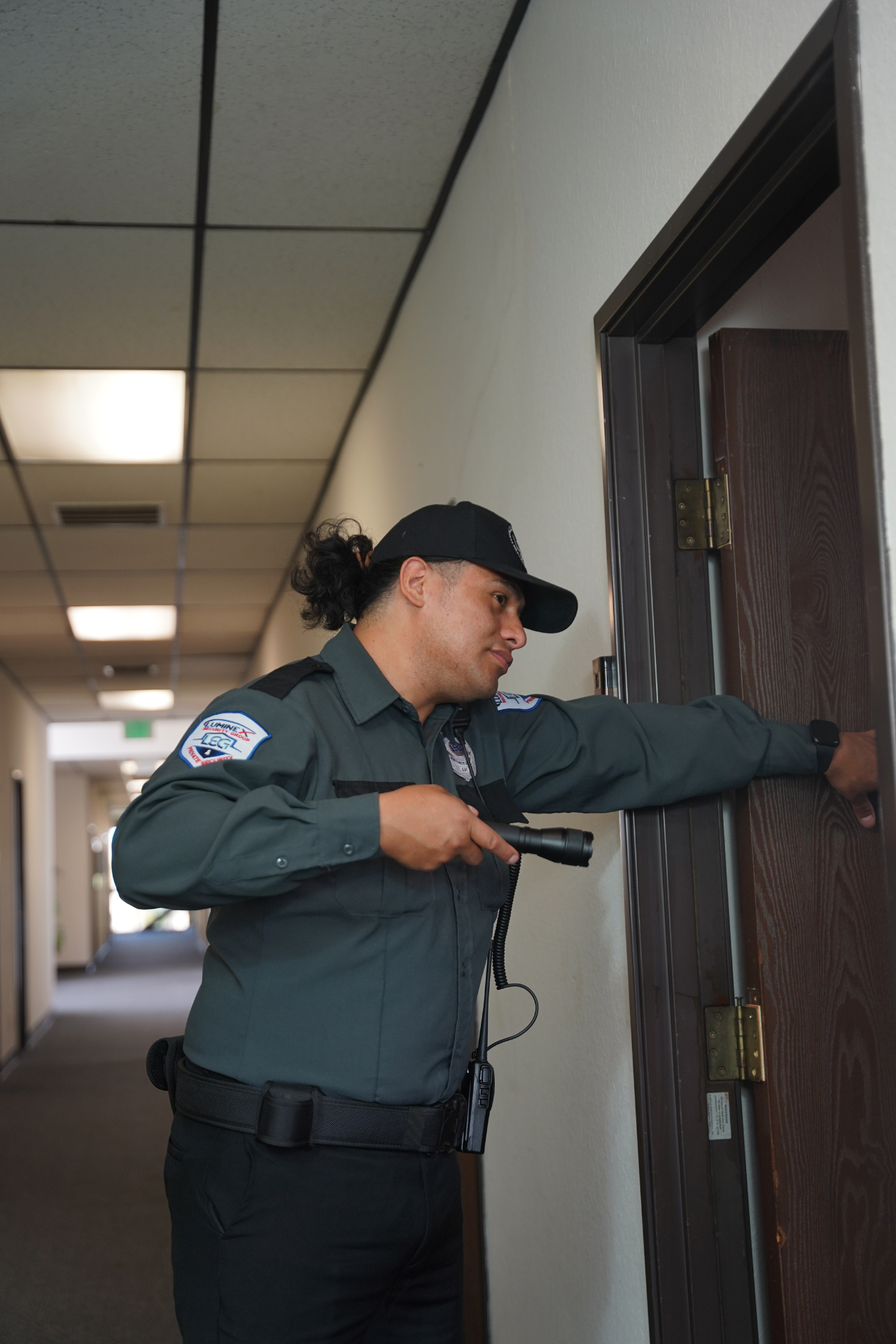 Luminex officer checking an interior doorway while holding a flashlight during a patrol round